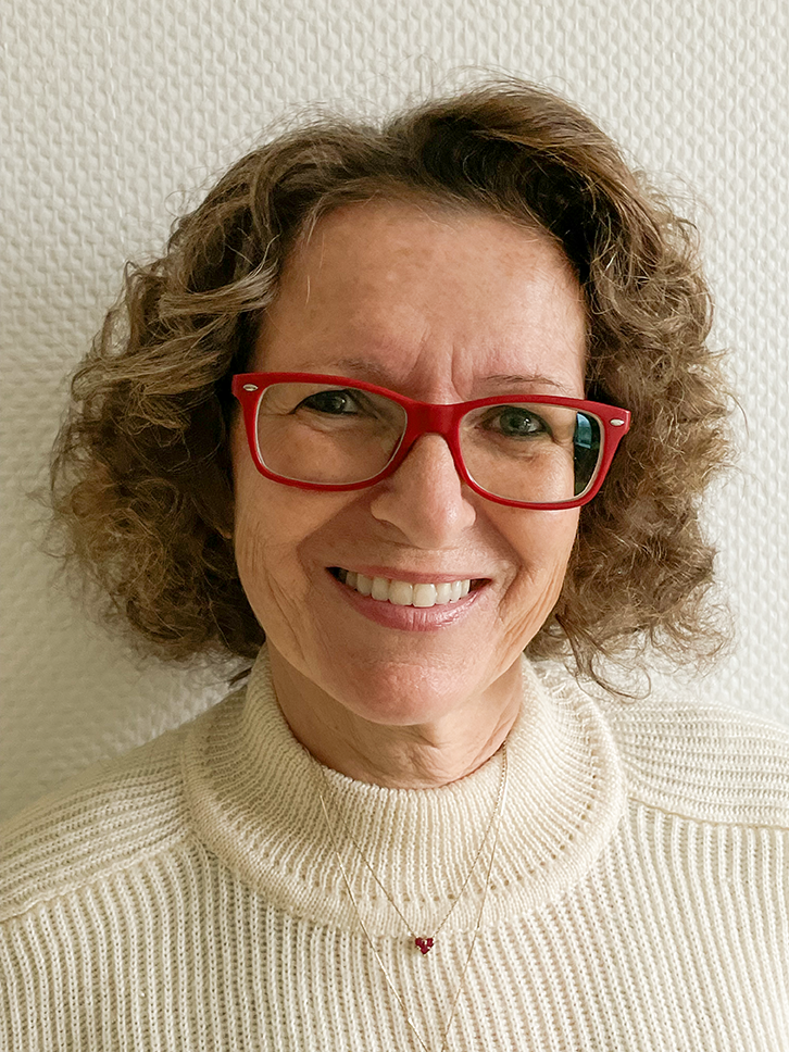 Portrait of Vivienne O. Jaeger wearing red glasses and a light-colored sweater against a neutral background.